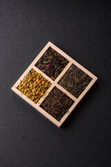 A wooden box with several types of dried tea, green, black, fruit, and chamomile. Dry tea in the box