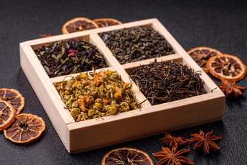 A wooden box with several types of dried tea, green, black, fruit, and chamomile. Dry tea in the box
