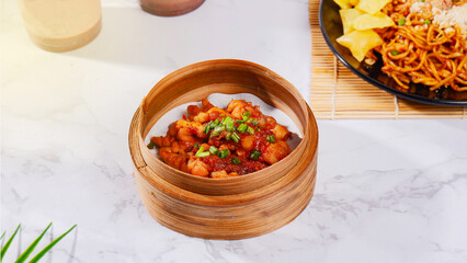 Steamed dish of spicy shrimp and vegetables in a bamboo steamer, with noodles and a drink in the background.