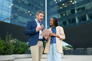 Business colleagues discussing data using tablet outdoors