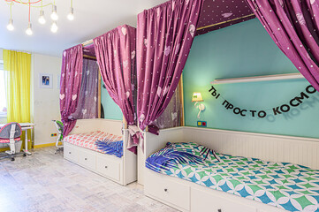Charming kids' bedroom featuring two canopy beds draped in purple heart-patterned curtains, set against a vibrant blue and yellow backdrop