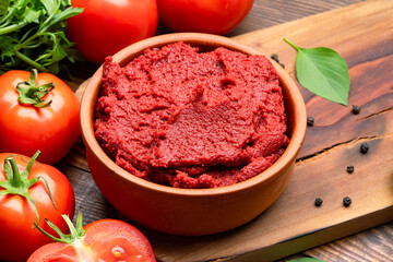 Fresh tomato paste or puree on wooden background	