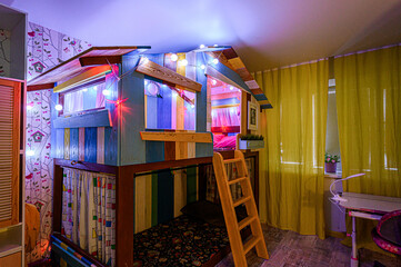 Cozy kids room featuring a colorful wooden treehouse bed, fairy lights, and whimsical decor. Yellow curtains soften the room