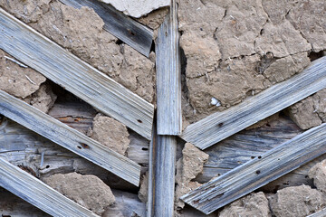 Old wooden wall covered with plaster. old laths on the walls. The plaster has fallen off. The wall needs repair. Close-up, background photo, space for text.