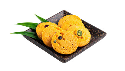 Stacked, round, golden-yellow treats on a dark wooden plate, with tropical leaves