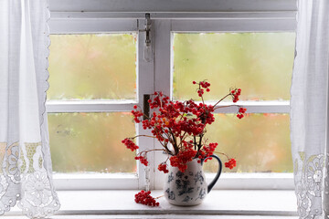 viburnum branches in a jug on window