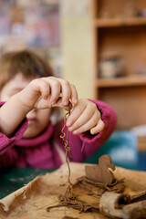 A preschool girl is engaged in clay modeling in a ceramics class. Every Saturday, the children are eager to go to their ceramics class and create pottery.