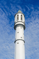 Mosque minaret rising against a bright blue sky, symbolizing Islamic architecture and serving multiple functions as a call to prayer tower, cultural landmark, and architectural heritage.