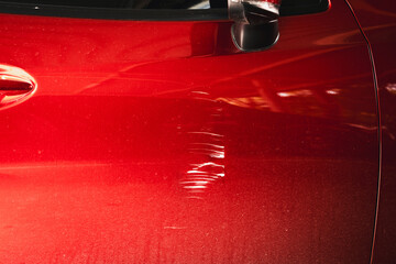 Close-up scratch damage on red car door, showing accident mark, paint abrasion, vehicle repair concept, insurance claim, automotive maintenance and problem detail for garage or workshop.