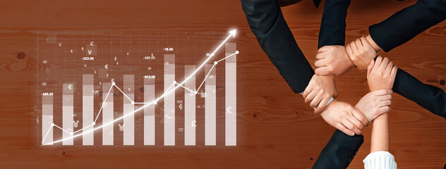Diverse hands join together in unity on a wooden table, symbolizing teamwork and collaboration, with an overlay of financial growth data and graphical insights. Axiom