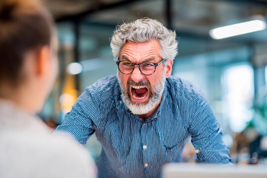 A man with gray hair and glasses passionately argues with a woman in a contemporary office. Tension fills the air as they engage in a spirited conversation