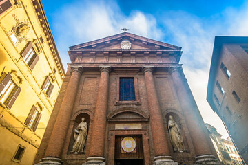 Naklejka premium Vivid photo of a colorful street in Siena historic center showing traditional Tuscan buildings, stone facades, flags, narrow alleyways and charming medieval atmosphere in Italy