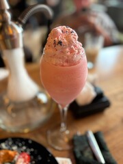 Pink milkshake topped with whipped cream served in a glass cup  