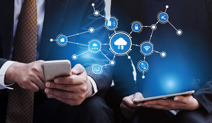 Two business professionals are using mobile devices, immersed in cloud computing concepts, showcasing modern technology and connectivity in a corporate setting. Tessel