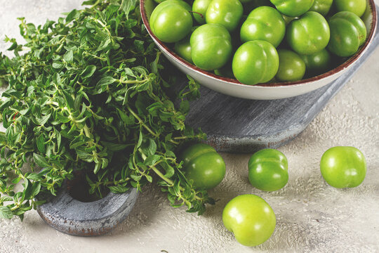 Tkemali, green cherry plum, in a bowl, on a gray table, top view, natural light, no people,