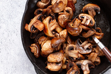 fried mushrooms champignons. on a cast-iron frying pan, natural light, close-up,