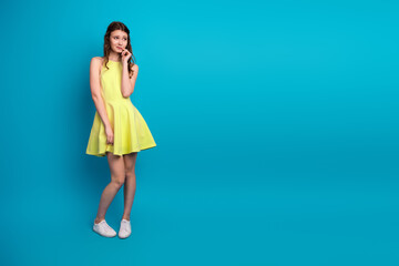 Young woman in a yellow dress holding a phone, standing against a vibrant blue background with a modern style