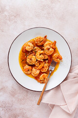 Savory shrimp dish served in a white plate with flavorful sauce and herbs