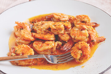 Savory shrimp dish served in a white plate with flavorful sauce and herbs