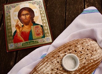 An Orthodox icon of the Savior beside bread and salt on a white towel symbolizes the traditional ritual of hospitality and blessing on a wedding day.
