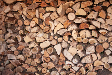 Stack of chopped firewood arranged in dense layers. A close-up rustic scene capturing texture, seasonal preparation, and natural material contrast