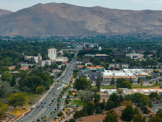 Obraz premium Carson City, Nevada is seen from above, featuring a central road, urban areas, greenery, and arid mountains dominating the horizon.