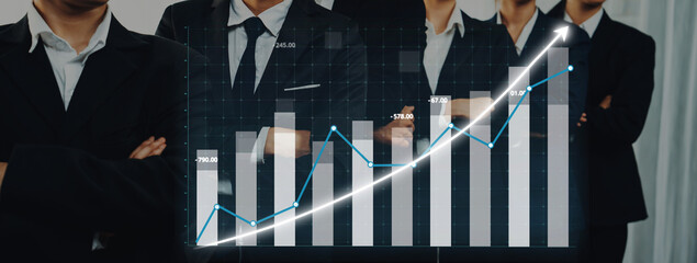 Business professionals in suits analyze financial growth trends using a digital graph with bar and line charts, showcasing teamwork and corporate strategy. Axiom