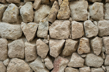 Brown and gray stone wall made of rough, irregularly shaped stones in a close-up view