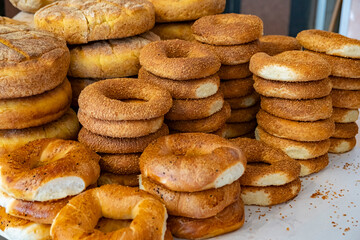 Freshly baked bagels and bread stacked in a bakery showcasing a variety of colors and textures, captured in the early morning light