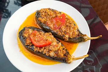 Delicious stuffed eggplants served with tomato on a white plate in a vibrant eatery