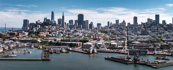 Aerial view of San Francisco, California, featuring the downtown skyline, Salesforce Tower, Transamerica Pyramid, Bay Bridge, and waterfront piers. © Aerial Film Studio