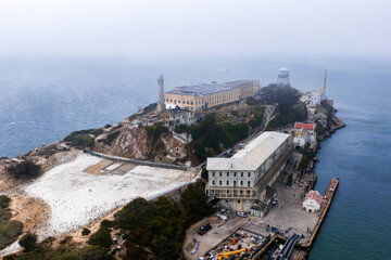 Aerial view of Alcatraz Island in San Francisco Bay, featuring the cellhouse, lighthouse, water tower, rugged terrain, and surrounding blue waters.