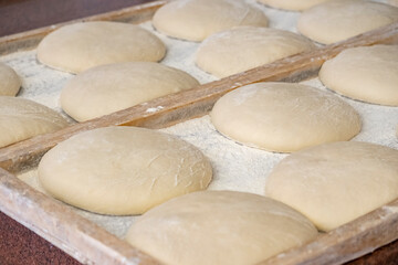 Dough resting in a wooden tray at a bakery before baking