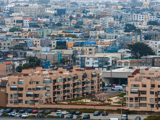 Fototapeta premium Dense urban area in San Francisco featuring pastel and vibrant houses, beige apartments with rounded windows, and landscaped courtyards.