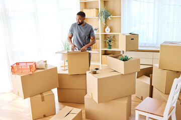 Portrait of a young man guy unpacking boxes after moving in and relocation in a new apartment, or packing to move out