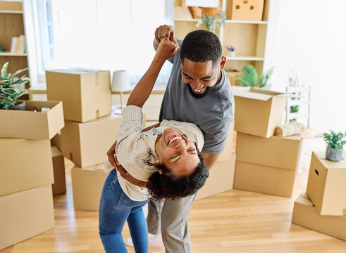 Portrait of a young couple unpacking, dancing, moving in and relocation to a new apartment, happy young couple family new beginning