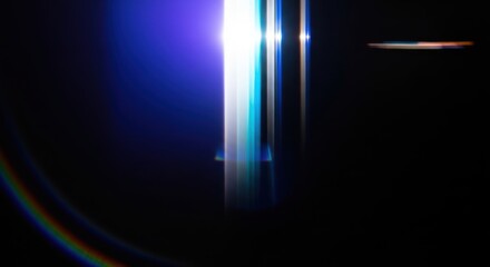 Abstract vertical light streaks with lens flare and rainbow hues on black background