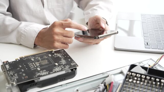 Closeup hand of computer hardware technician using phone while dissemble and  fixing computer PC.