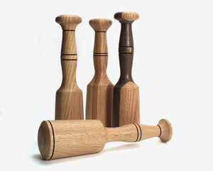 A group of four handcrafted wooden mallets on a white background.  Three of the mallets are vertical and one is horizontal.  The mallets are lathe turned and a good example of artisan woodworking.