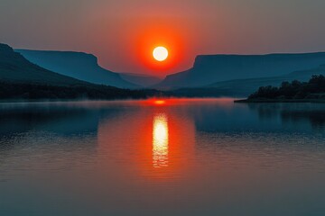 Fototapeta premium Vibrant orange sunset over a serene lake, reflecting perfectly between dramatic silhouetted mountains, creating a tranquil, breathtaking scene.