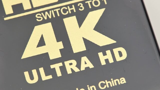 Macro closeup of a generic 4k UHD video logo symbol on electronic equipment, capture card monitor, high resolution abstract concept, no people, 4k hi res material icon on device surface up close