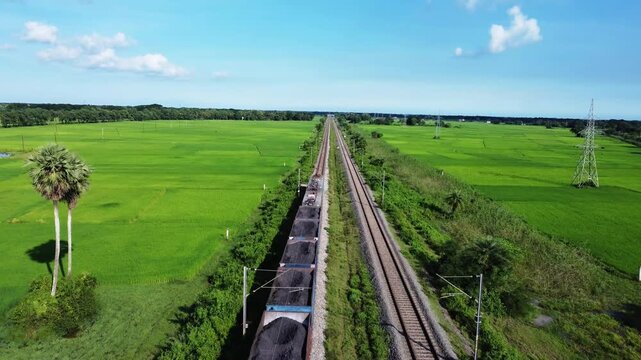 Coal transportation.  train wagons loaded with coal and goes to a sea port. Coal train crossing in middle of agriculture fields. Coal train moving towards Paradeep port , INDIA.