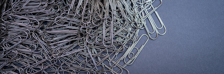A chaotic yet captivating close-up of numerous metallic paper clips in a monochrome palette,...