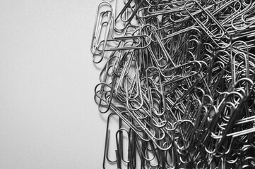 A chaotic yet captivating close-up of numerous metallic paper clips in a monochrome palette,...