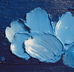 Close-up of textured, thick, vibrant blue and white paint strokes on a dark blue surface