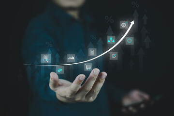 Businessman showing digital growth chart and technology icons in virtual interface.