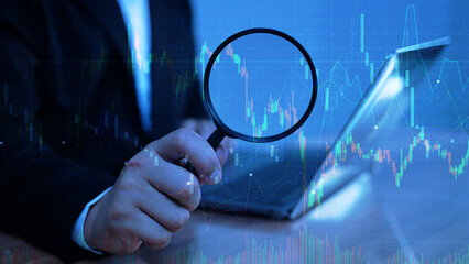 Business data analysis concept with magnifying glass and digital chart on laptop screen.