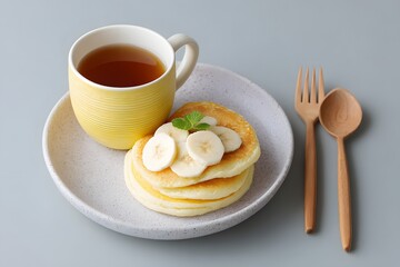 Stack Of Fluffy Pancakes With Banana, Sweet Breakfast With Tea, Simple Dessert Serving, Minimalist Food Photography, Cozy Morning Meal, Wooden Cutlery And Yellow Mug, Top Down View