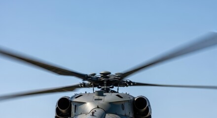 Military helicopter with spinning rotor blades against a clear blue sky. Aviation technology and transportation concept for defense.
