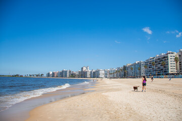 girl walking with dog on playa de los pocitos in montevideo in uruguay on a sunny day